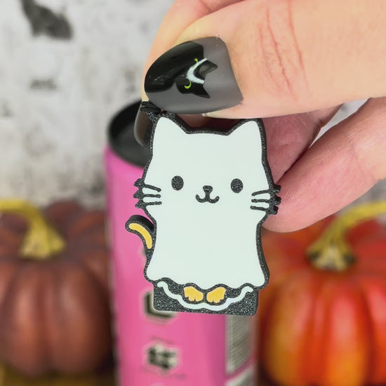 a ghost cat-shaped Tab Buddy is used to open a pink can of soda. A ghost dog Tab Buddy also is shown peeping into frame.