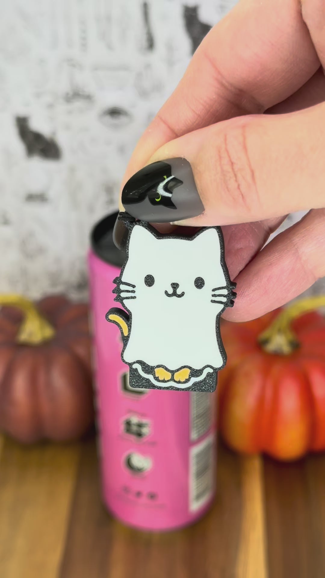a ghost cat-shaped Tab Buddy is used to open a pink can of soda. A ghost dog Tab Buddy also is shown peeping into frame.