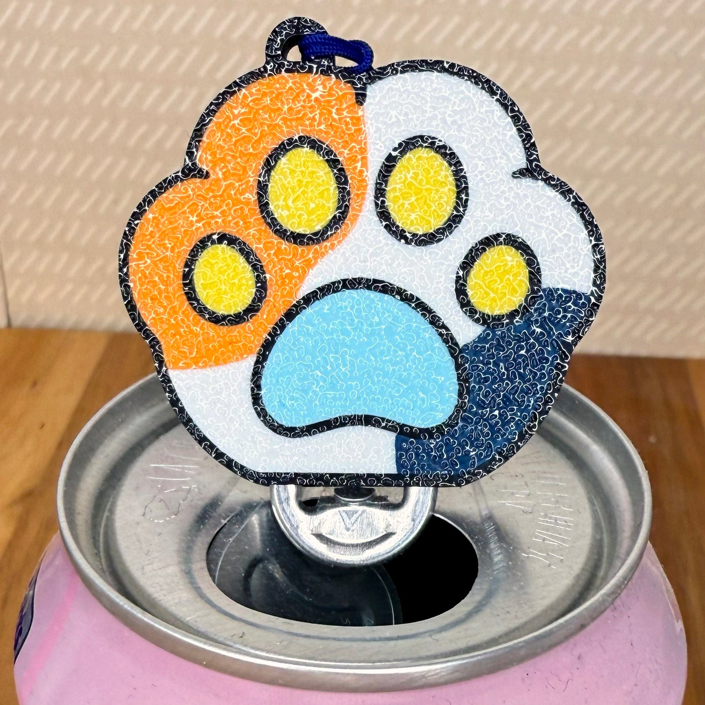 Colorful paw-shaped Tab Buddy on a can with a neutral background