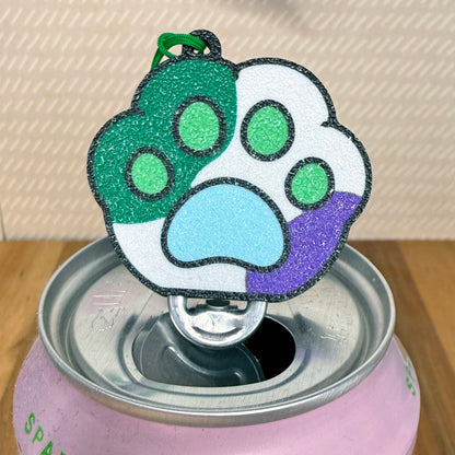 Colorful green, blue and purple Pride paw print Tab Buddy on a can opener sits atop a pink can