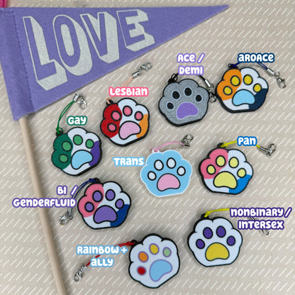 Set of paw-shaped Pride Paw Tab Buddies with labels for different Pride flag color combinations on a light background.
