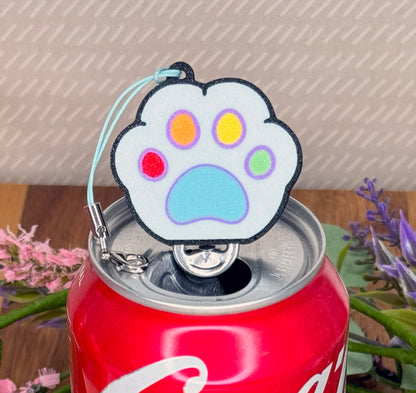 Colorful paw-shaped Tab Buddy with rainbow colors sits atop a Coca-Cola can with a blurred background