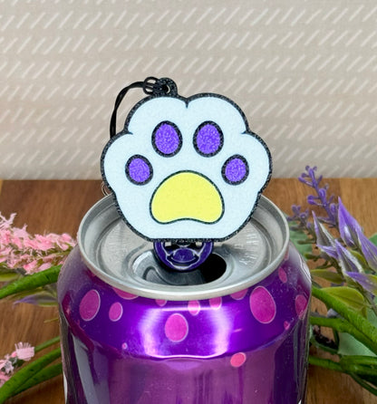 Purple soda can with a white, purple and yellow paw print Tab Buddy on top, surrounded by flowers.