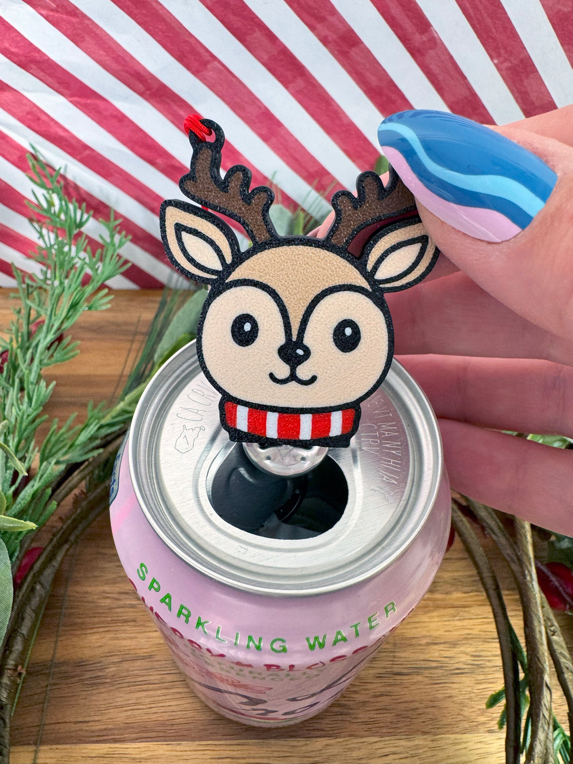 Reindeer-shaped Tab Buddy on a can of sparkling water with a striped background