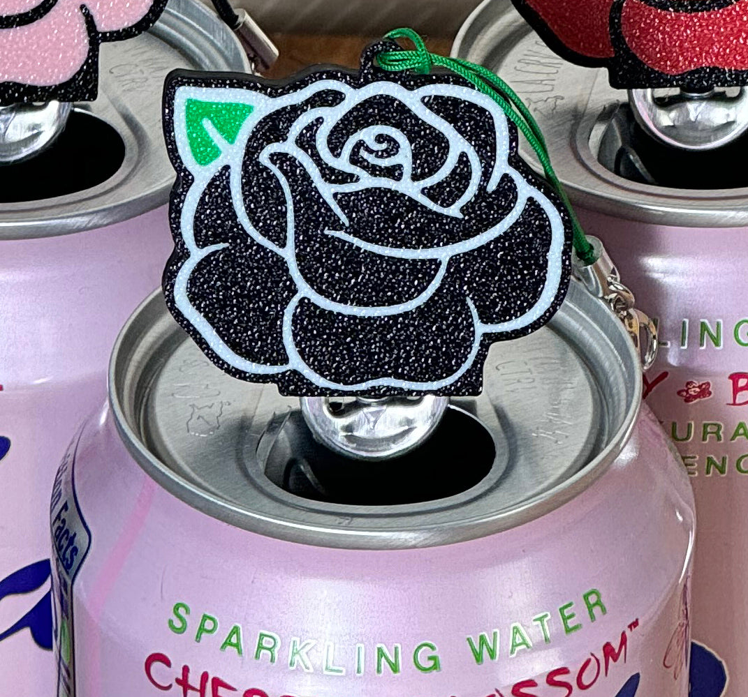 Pink sparkling water can with a black rose-shaped Tab Buddy keychain on top