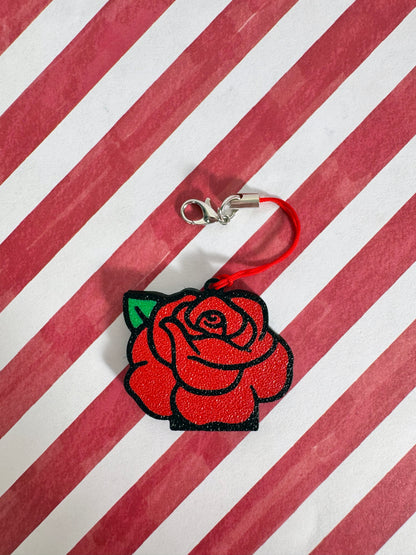 Red rose-shaped Tab Buddy keychain on a red and white striped background