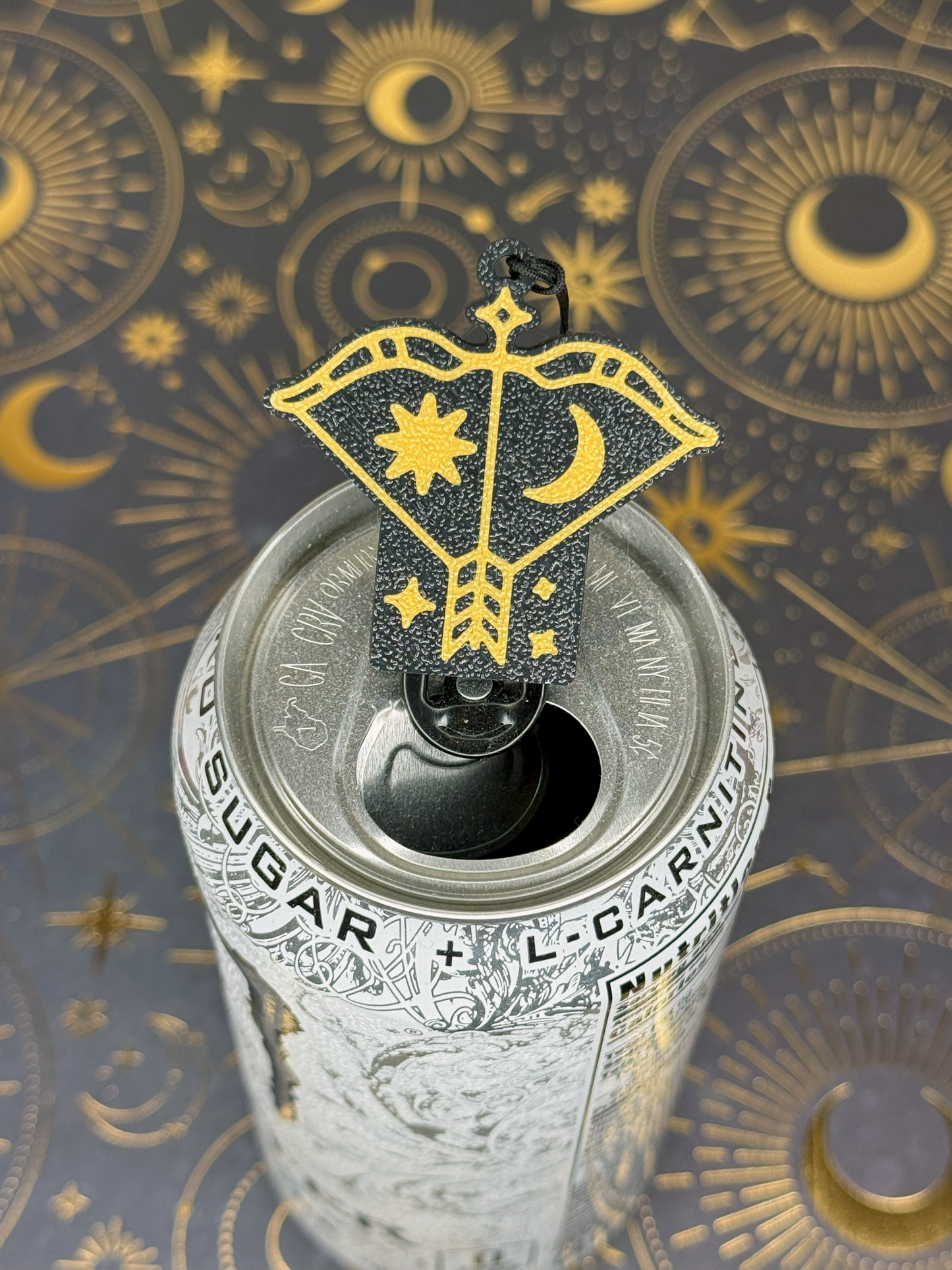 Decorative black and gold Sagittarius Tab Buddy with celestial design on a can against a mystical background