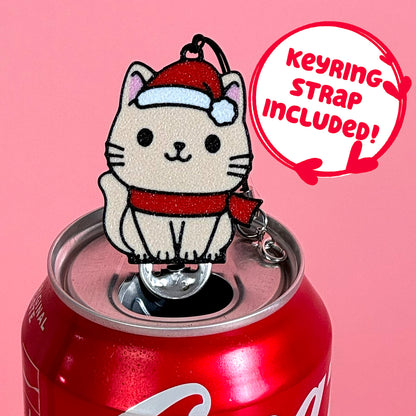 Santa cat Tab Buddy keychain sits atop a Coca-Cola can against a pink background