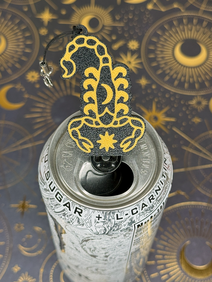Decorative Scorpio Zodiac Tab Buddy keychain with black and gold intricate design on a can against an ornate background