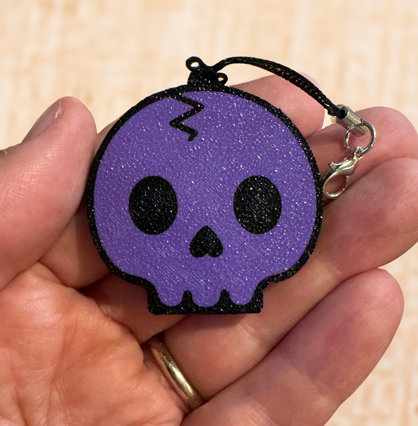 Purple skull-shaped Tab Buddy with black strap is held in a hand