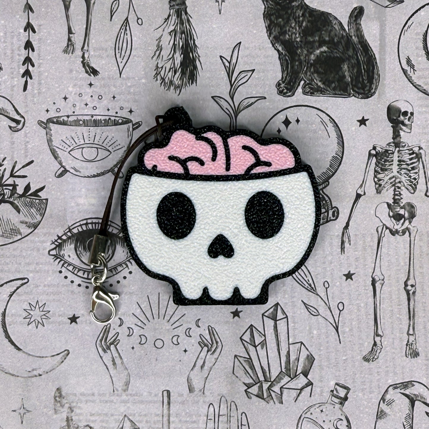 Skull Tab Buddy with pink brain on a gray background with occult symbols