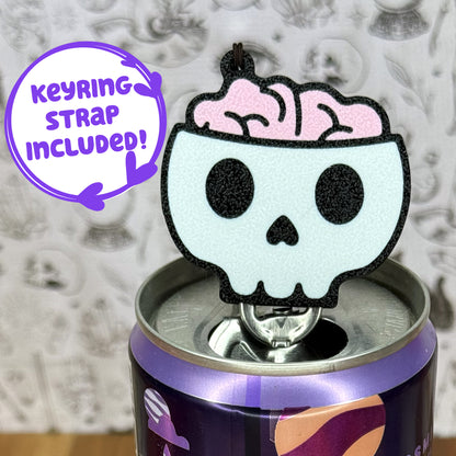 Skull-shaped Tab Buddy with pink brain on a purple can, keyring strap included text.