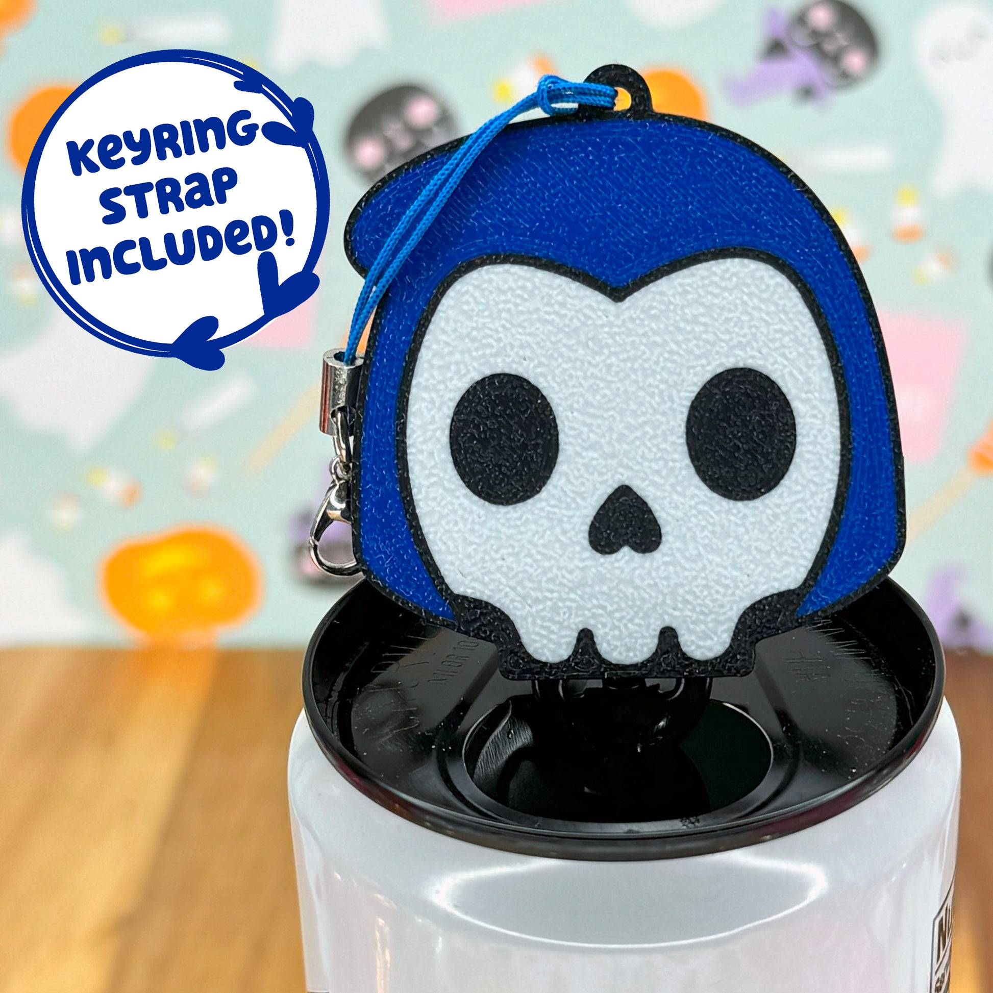 Blue hooded skull-shaped Tab Buddy with keyring strap on a colorful background