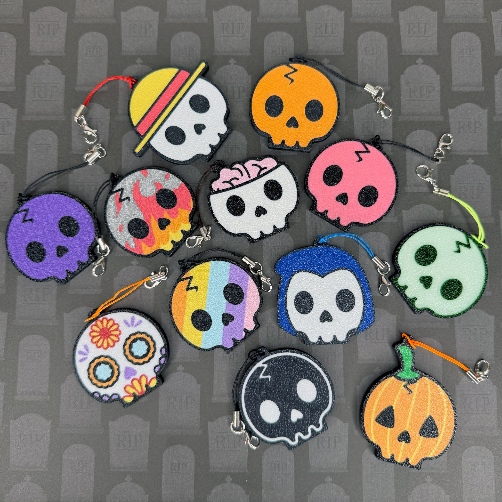 Group of various skull-shaped Tab Buddies against a black and grey background