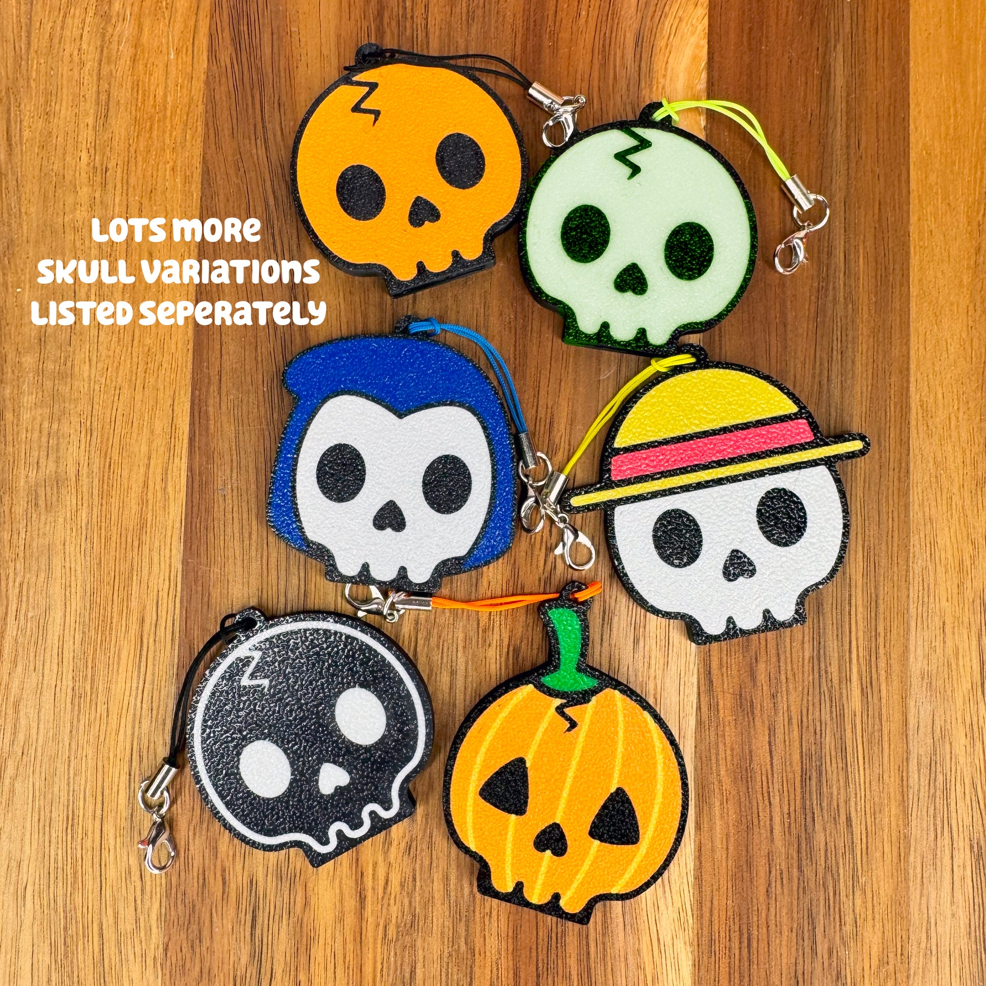 Set of colorful skull-shaped Tab Buddy keychains on a wooden surface with text overlay stating "lots more skull variations listed seperately."