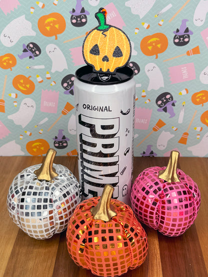 Energy drink can with a pumpkin skull-shaped Tab Buddy atop surrounded by pumpkins on a Halloween-themed background