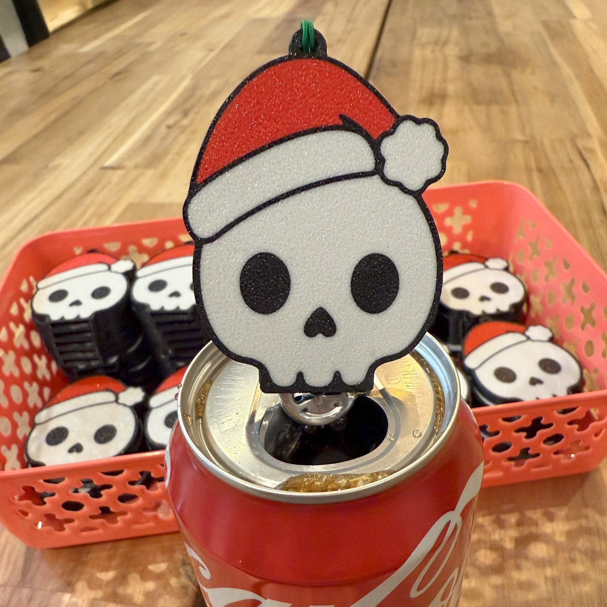 Santa skull-shaped Tab Buddy with on a Coca-Cola can, with more skull-shaped Tab Buddies in the background.