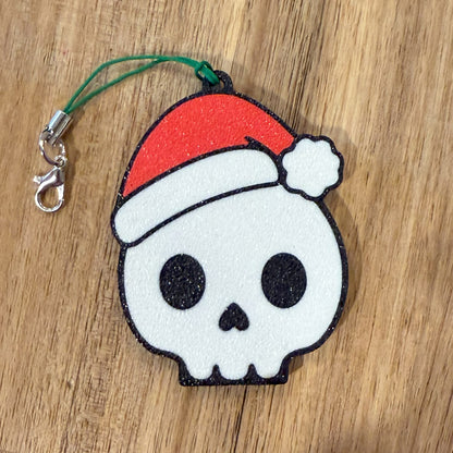 Skull-shaped Tab Buddy keychain with a red Santa hat on a wooden surface