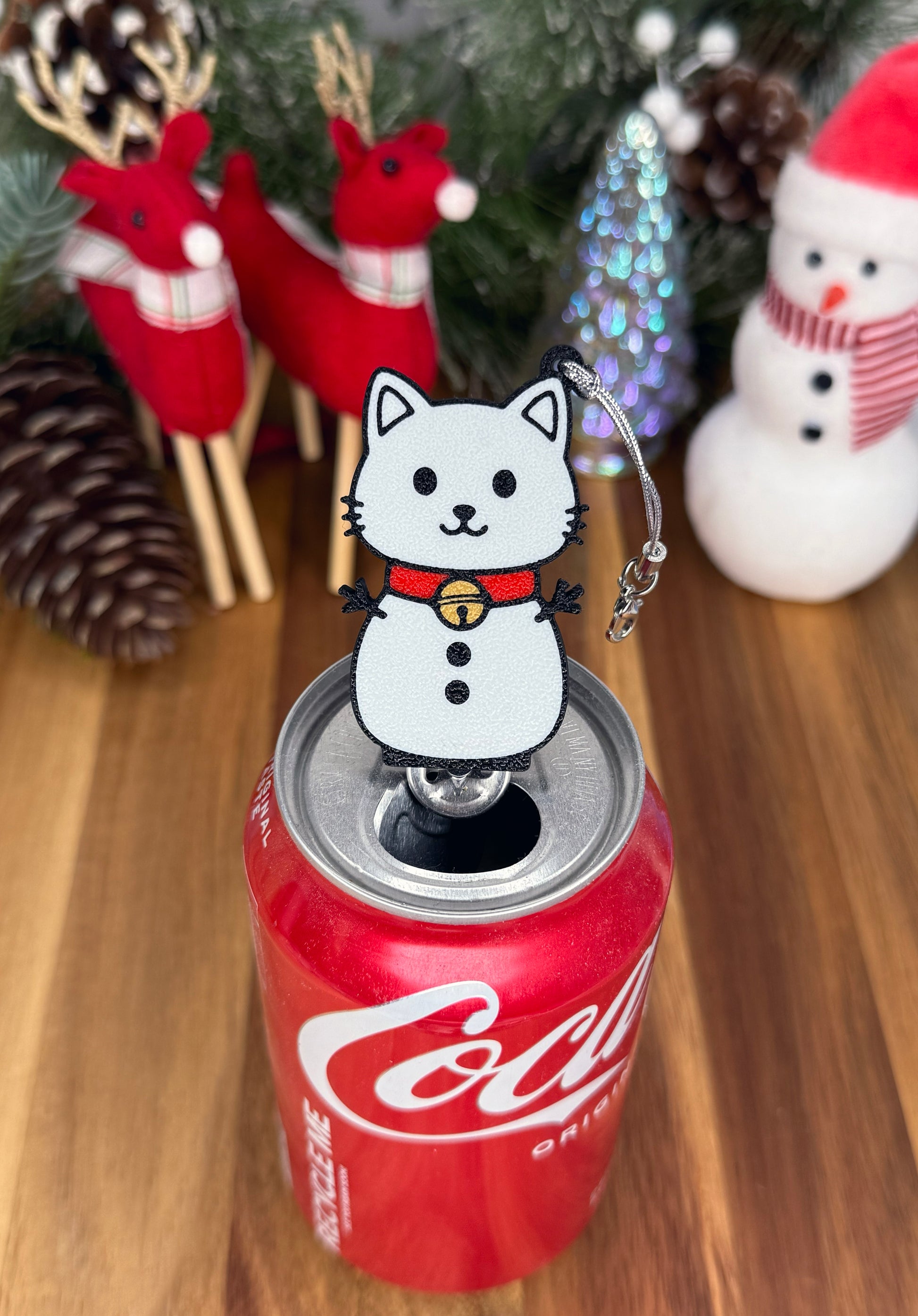Can with a cat-shaped Tab Buddy on a wooden surface with Christmas decorations.