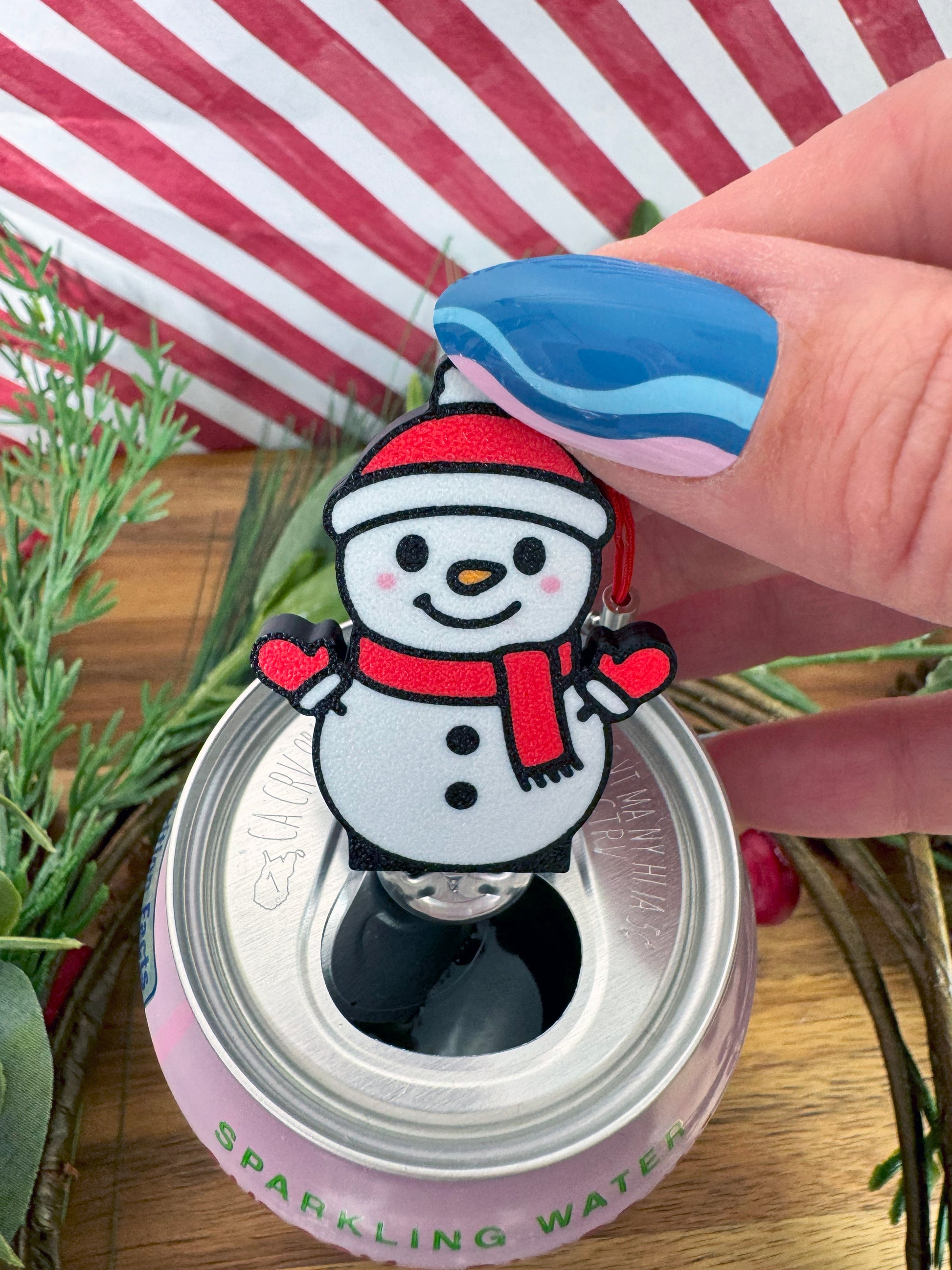 Snowman-shaped Tab Buddy on a can with a striped background