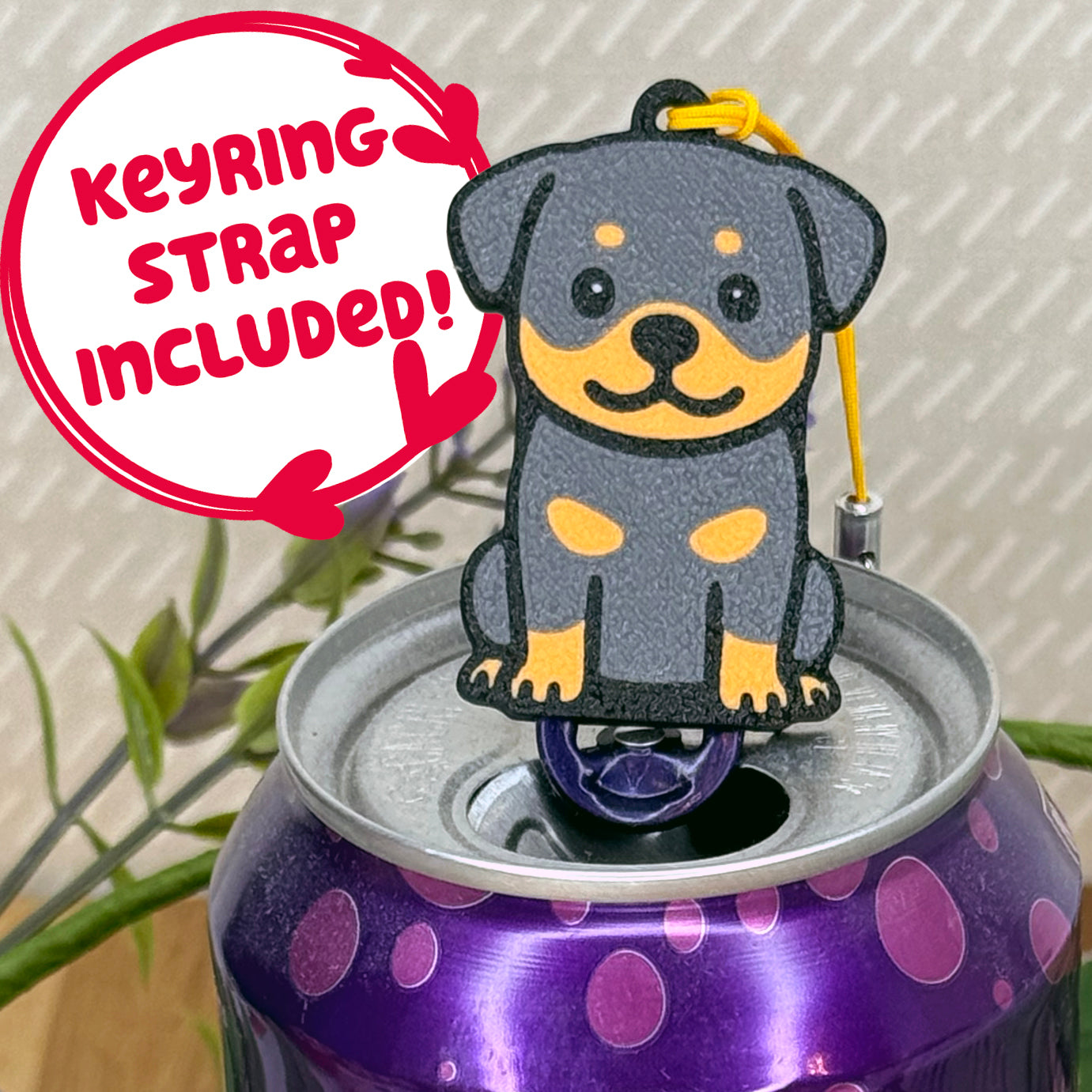 A cute Rottweiler design Tab Buddy rests atop an open can of sparkling water. Text bubble reads, "Keyring Strap Included!"