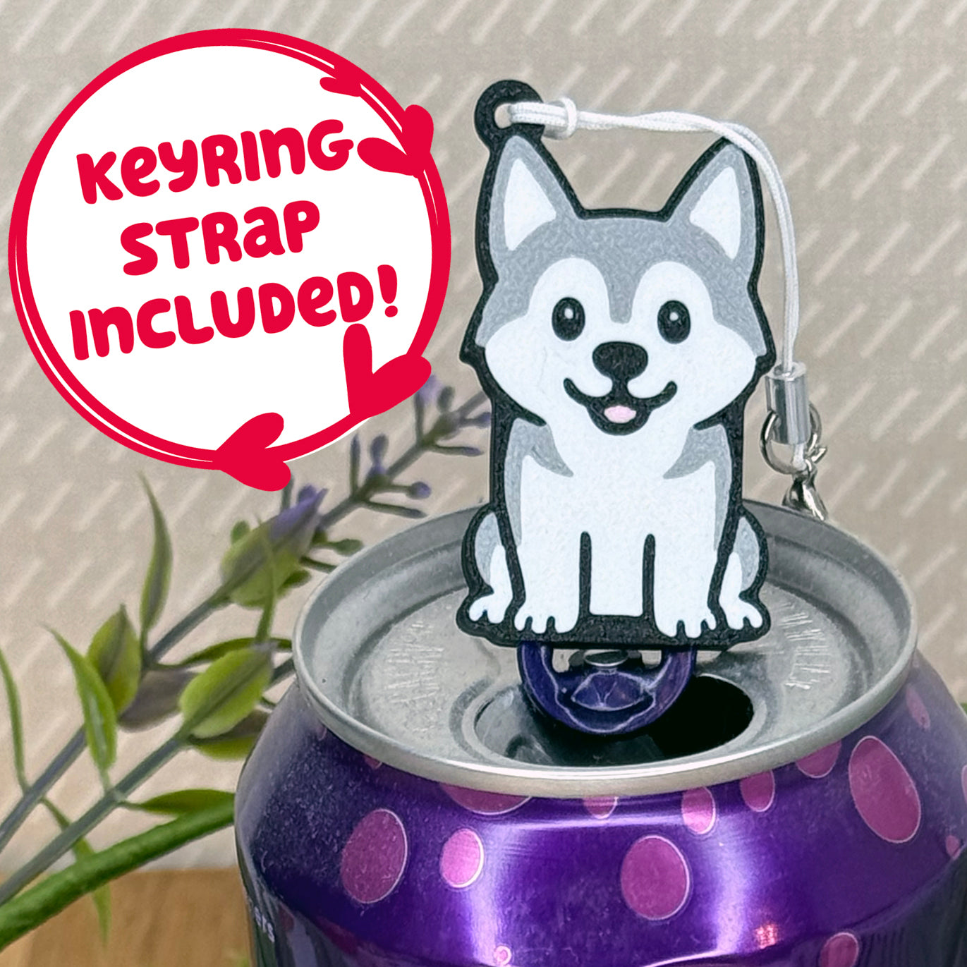 A cute grey and white Husky design Tab Buddy rests atop an open can of sparkling water. Text bubble reads, "Keyring Strap Included!"