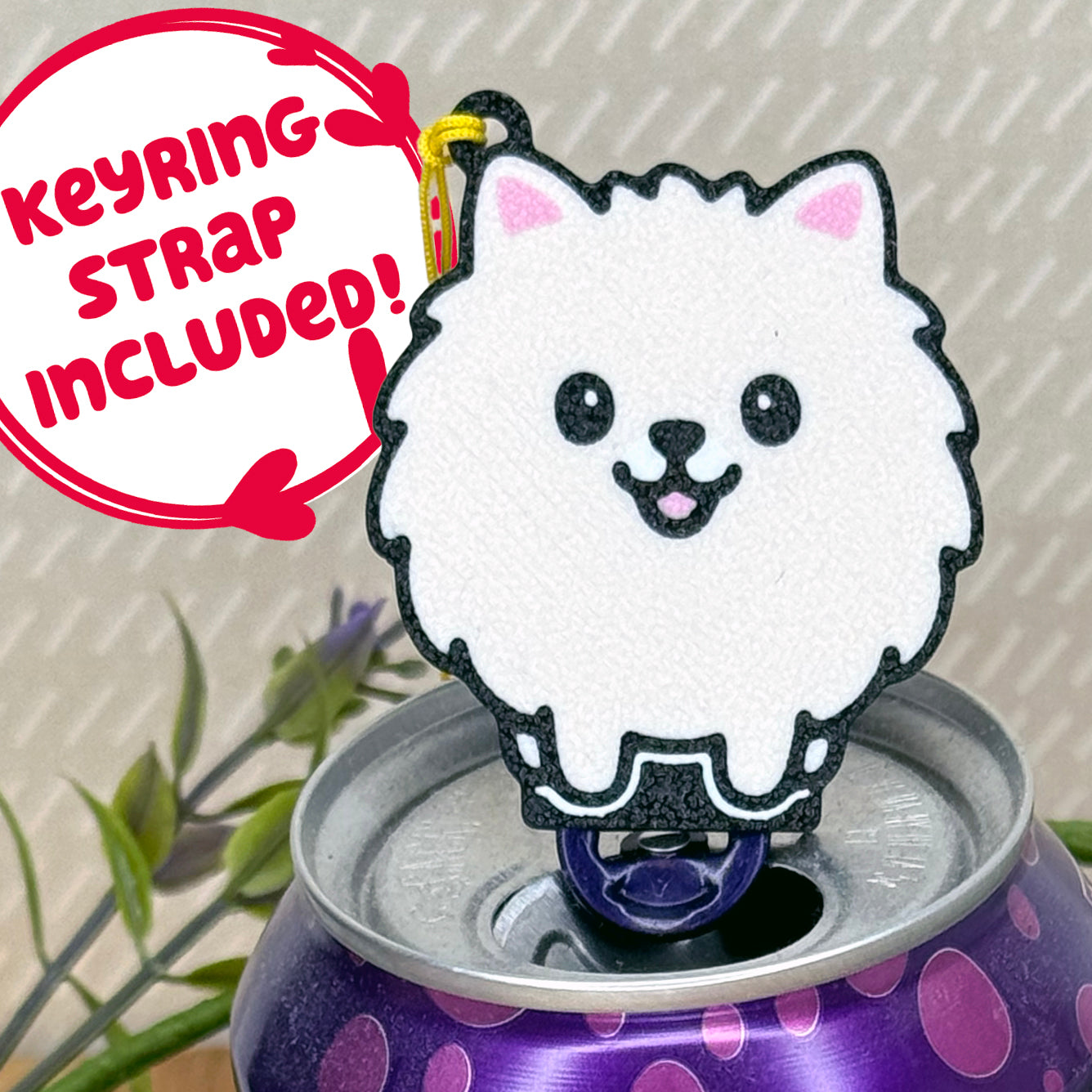 A cute Pomeranian design Tab Buddy rests atop an open can of sparkling water. Text bubble reads, "Keyring Strap Included!"