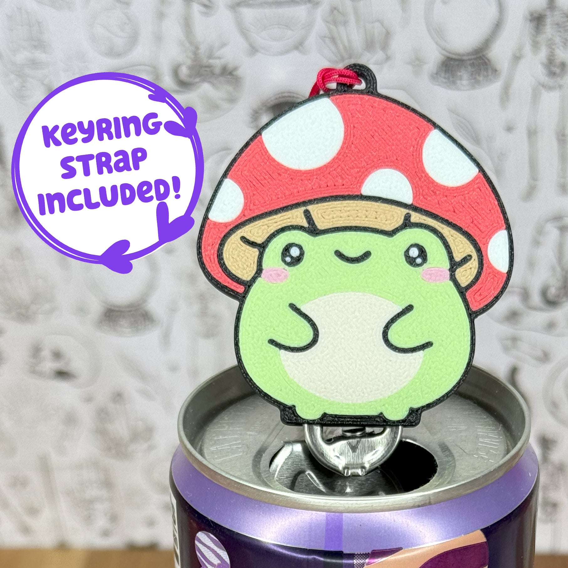 Tab Buddy of a toadstool frog on top of a can, against a textured gray background with text that reads 'keyring strap included'.