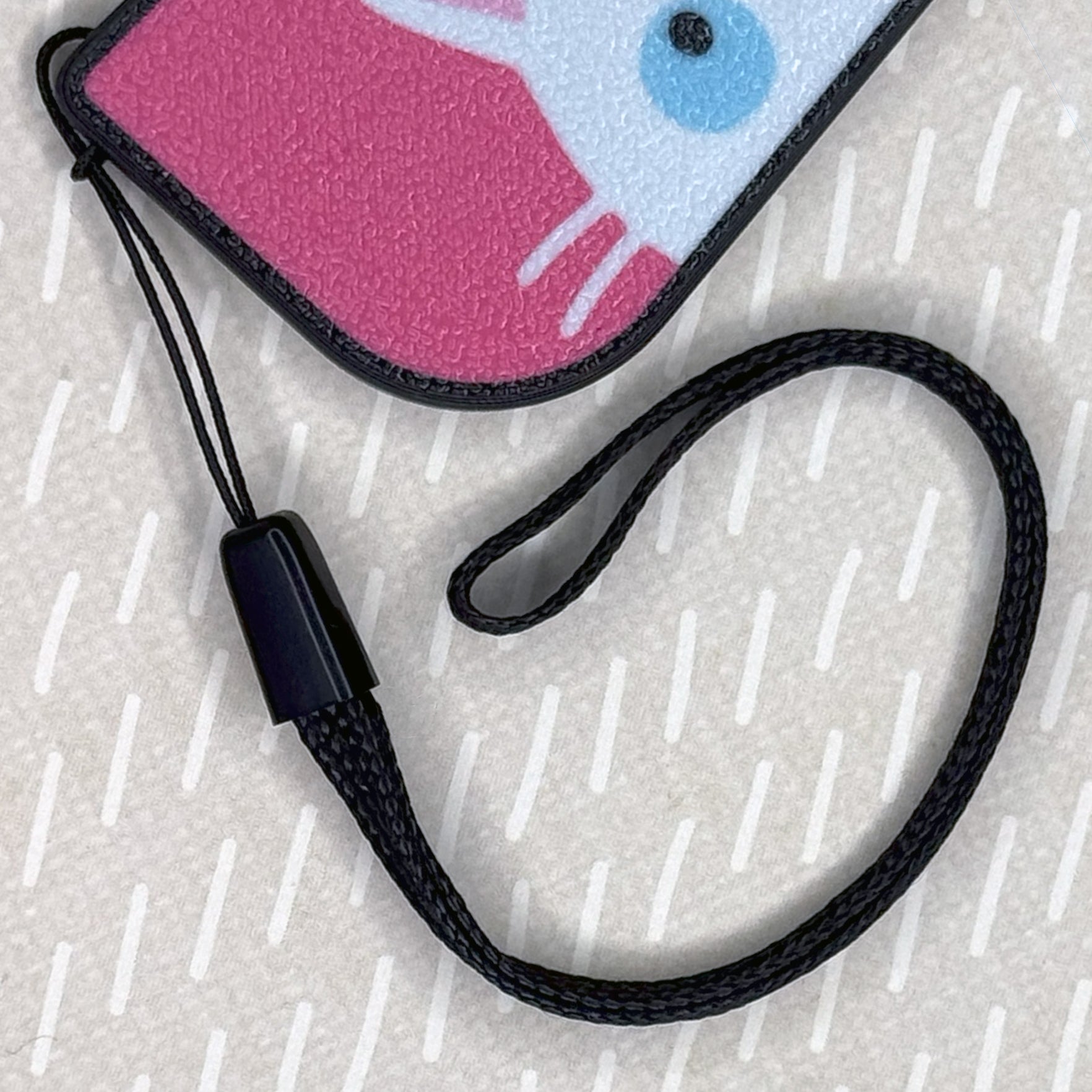 Black wrist strap is shown attached to matching cat-themed Tab buddy XL ono beige background