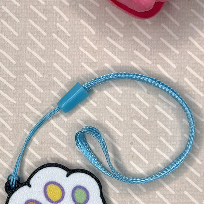 Blue wrist strap is shown attached to matching Kitty paw-shaped Tab Buddy on a textured surface