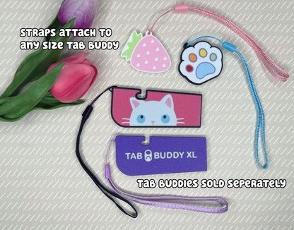 Four various Tab Buddies are shown with optional wrist straps attached. Text reads, "Straps attach to any size Tab Buddy. Tab Buddies sold seperately."