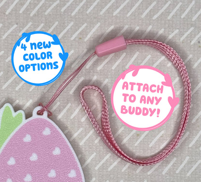 Pink wrist strap with strawberry-shaped Tab Buddy on a beige background