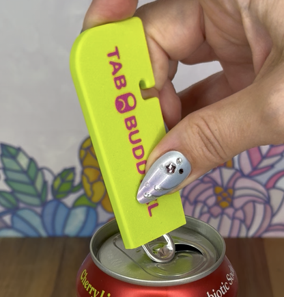 Hand using a yellow Tab Buddy XL on a red can with a colorful background.