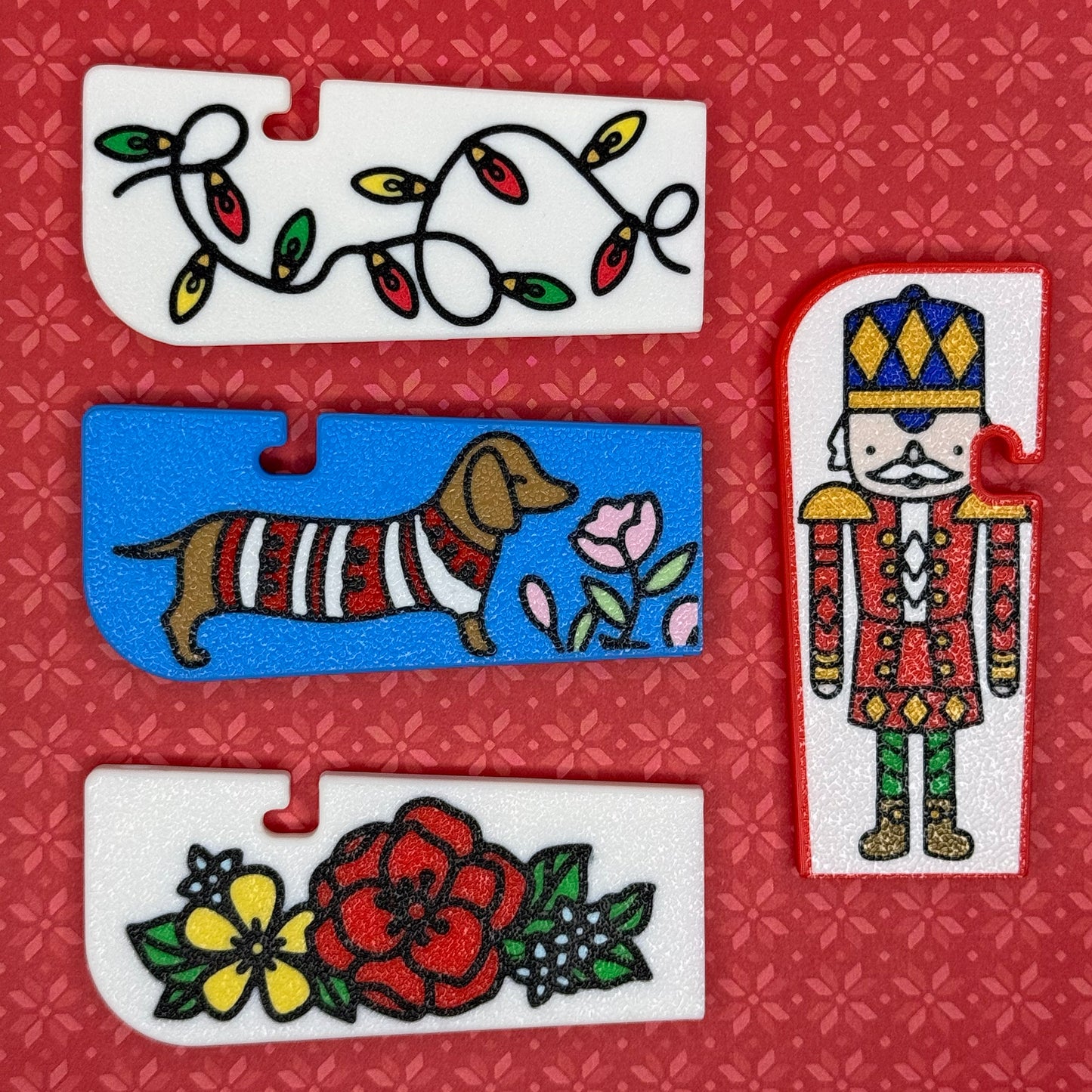 A collection of 4 Tab Buddy XLs with Christmas themes sit arranges on a red floral background.