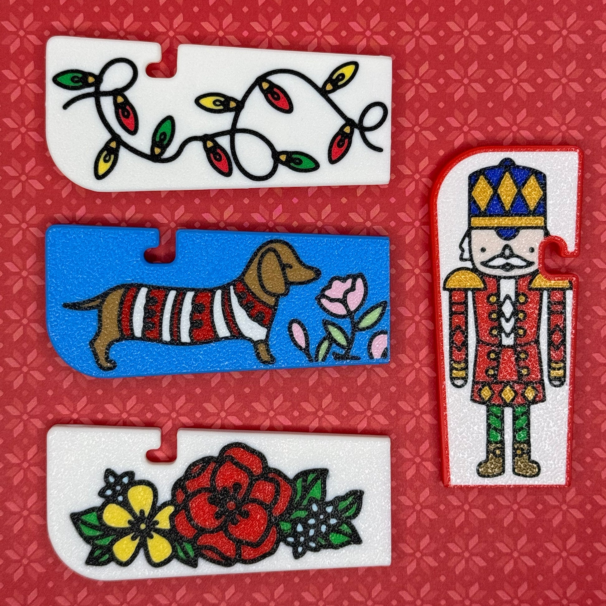 A collection of 4 Tab Buddy XLs with Christmas themes sit arranges on a red floral background.
