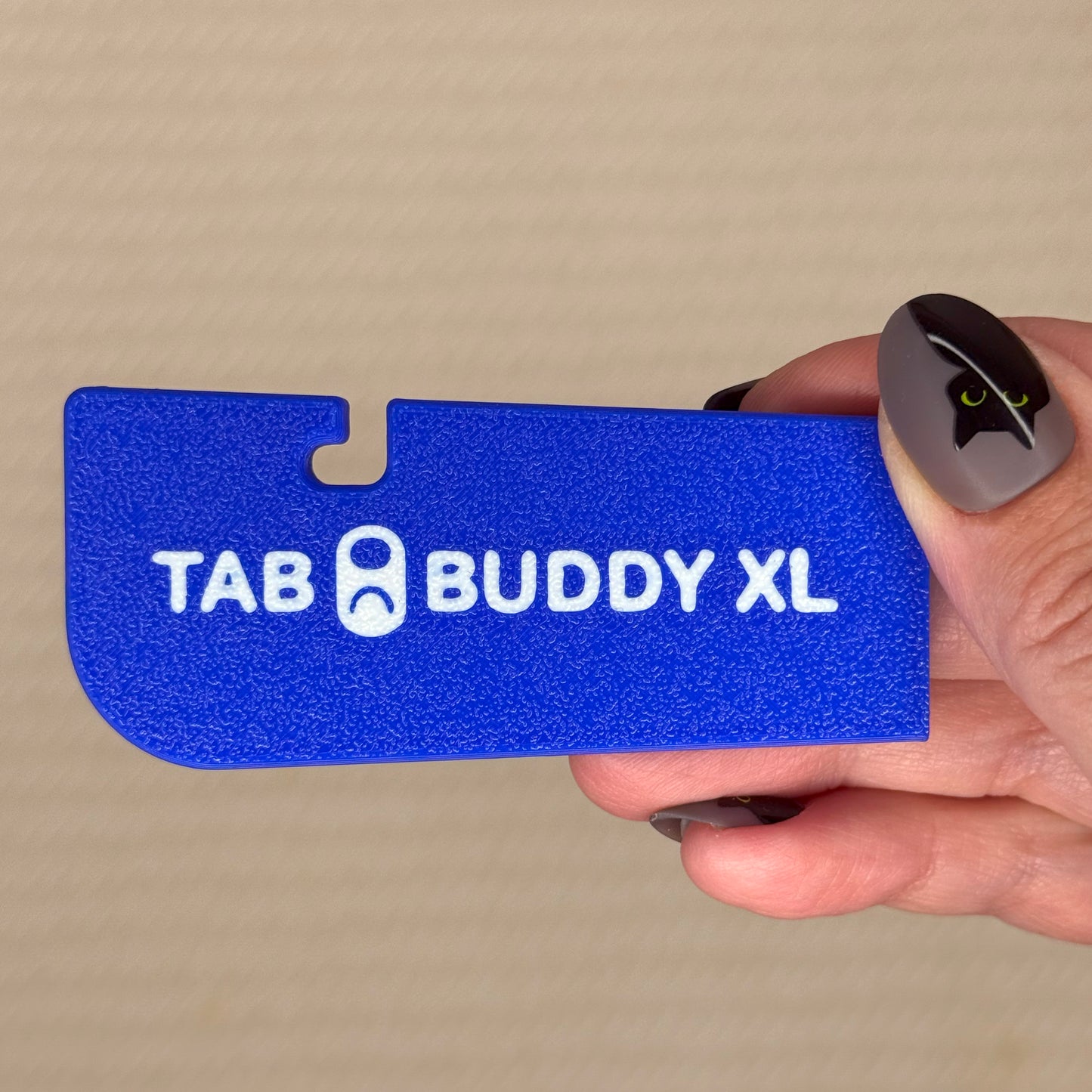 Deep Blue 'TAB BUDDY XL' product held by a hand against a beige background