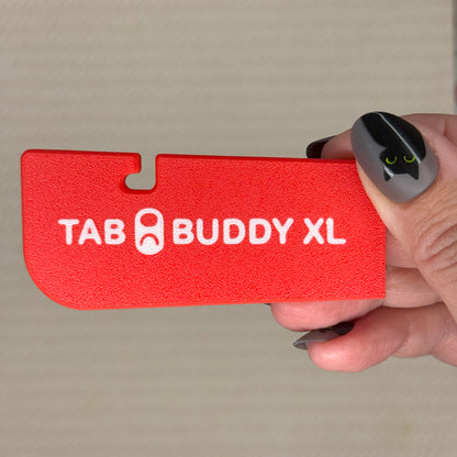 Red 'TAB BUDDY XL' product held by a hand against a neutral background
