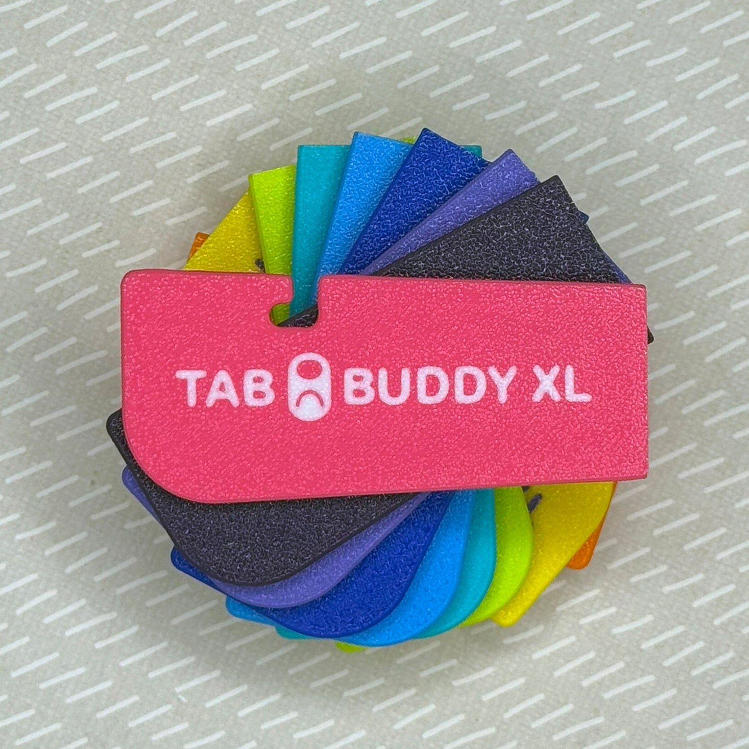 a swirling, colorful pile of Tab Buddy XLs on a textured gray background