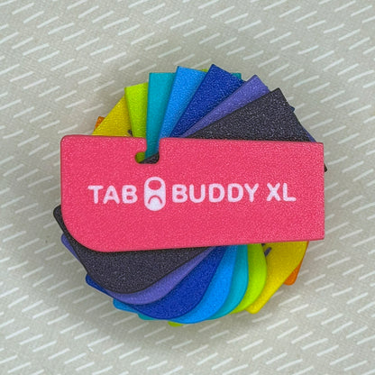 a swirling, colorful pile of Tab Buddy XLs on a textured gray background