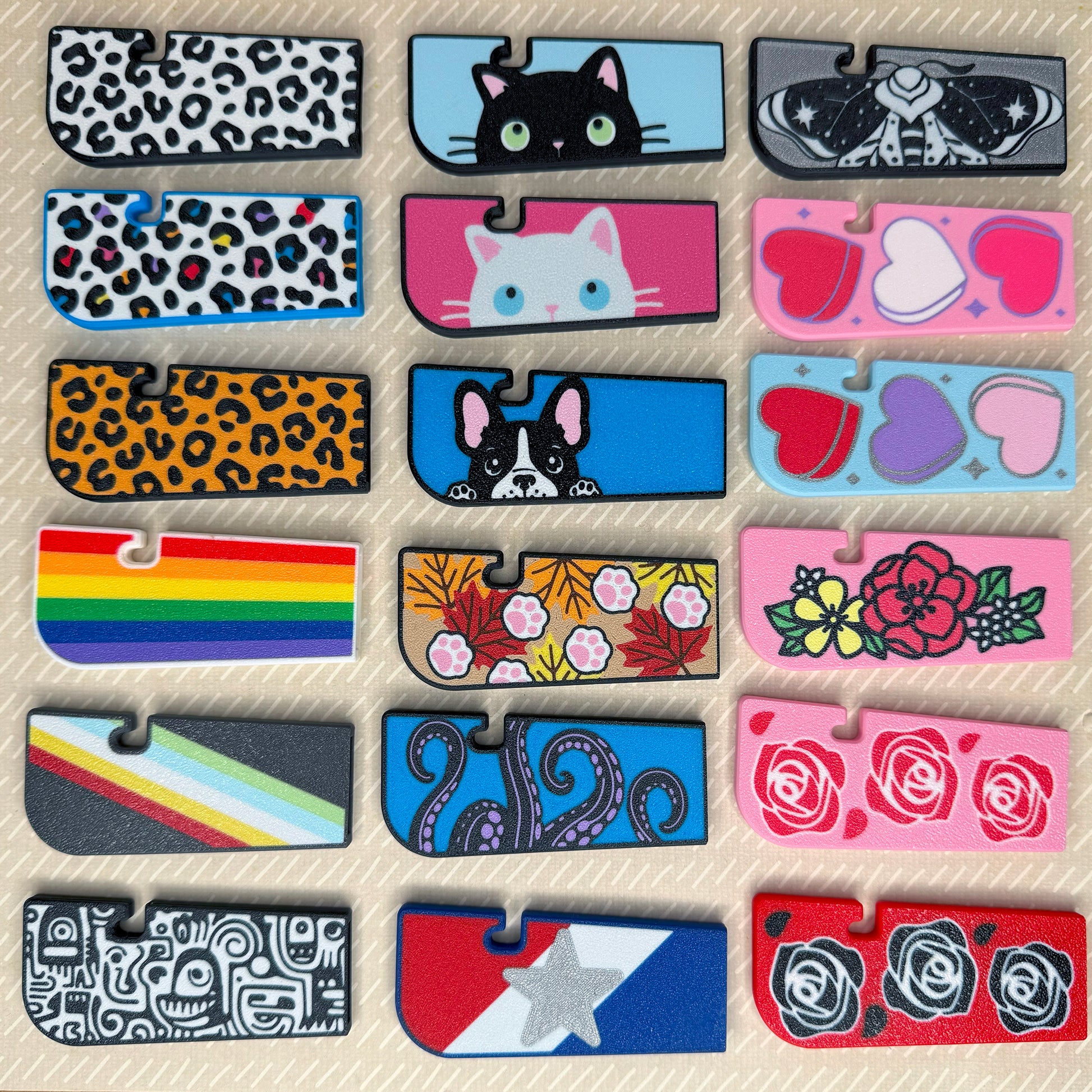 Collection of 18 colorful Tab Buddy XLs with various designs on a beige background