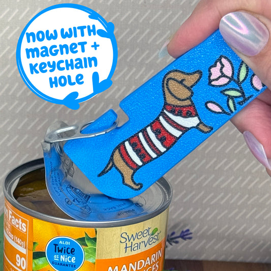 A sky blue Tab Buddy XL with image of a light brown dachshund dog smelling pink flowers opens a can of mandarin oranges.
