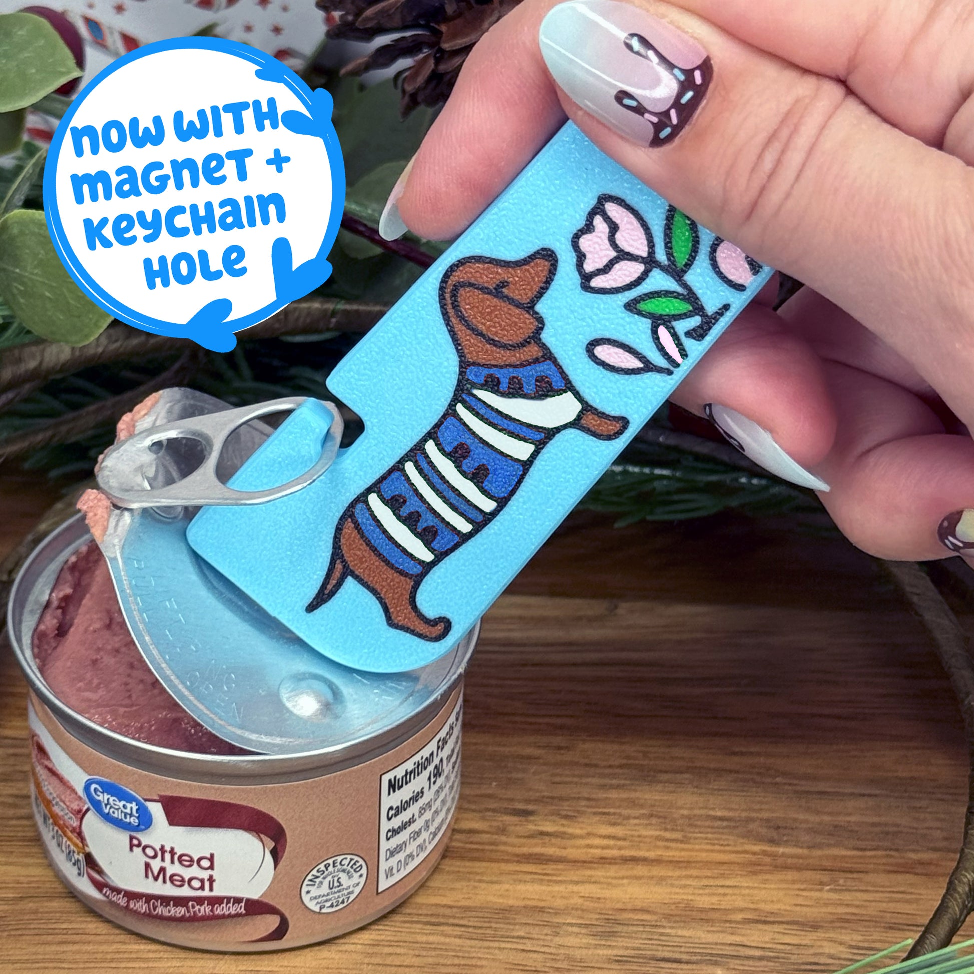 Hand holding a Tab Buddy XL can opener with a magnet and keychain hole feature, over a can of potted meat.
