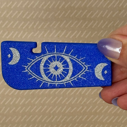 Blue Tab Buddy XL with silver eye design held by a hand against a beige background