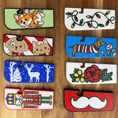 Collection of colorful Tab Buddy XL with various designs on a wooden surface