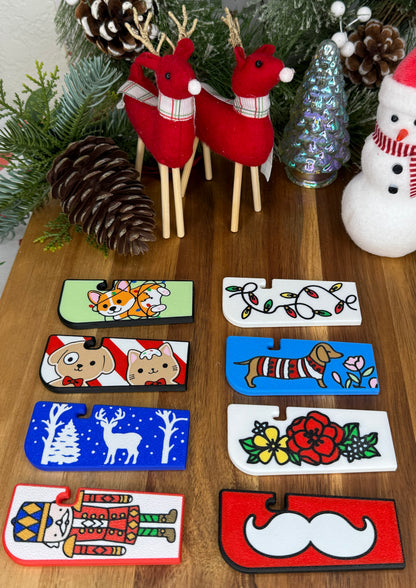 Set of decorative Tab Buddy XL with animal illustrations on a wooden surface with Christmas decorations.