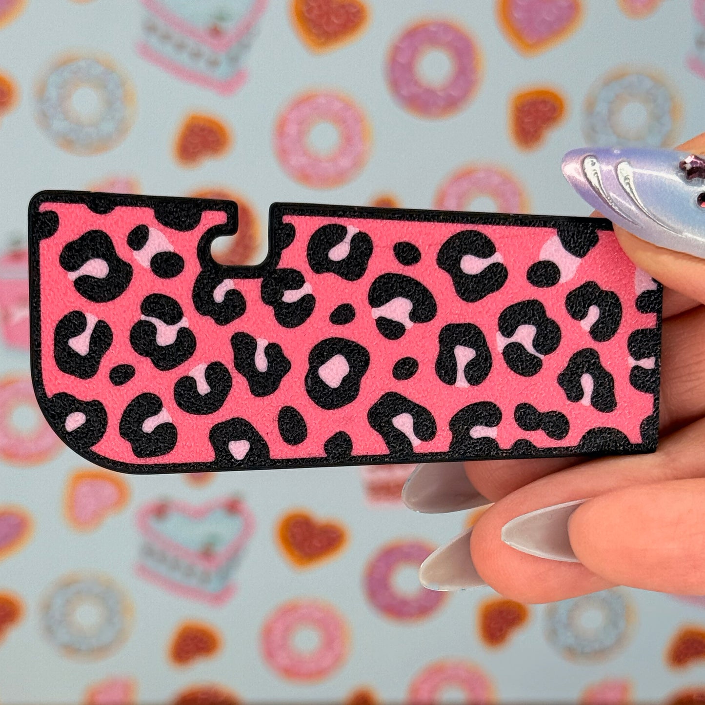 Pink and black leopard print Tab Buddy XL held by a hand with a colorful background.