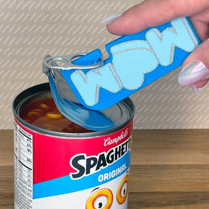 Hand using a blue Mom Tab Buddy XL to peel back the lid on a Campbell's Spaghetti-Os can.