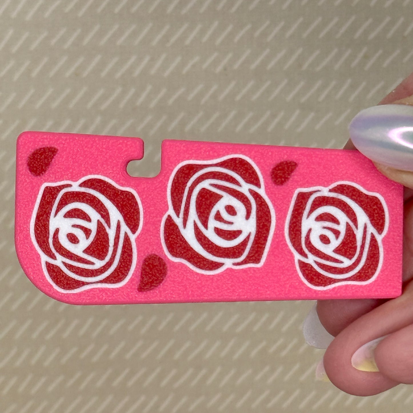 Pink Tab Buddy XL with red rose designs held by a hand against a patterned background
