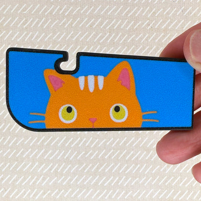 Tab Buddy XL with a orange cat illustration held by a hand on a textured beige background