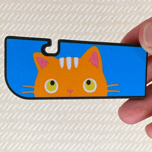 Tab Buddy XL with a orange cat illustration held by a hand on a textured beige background